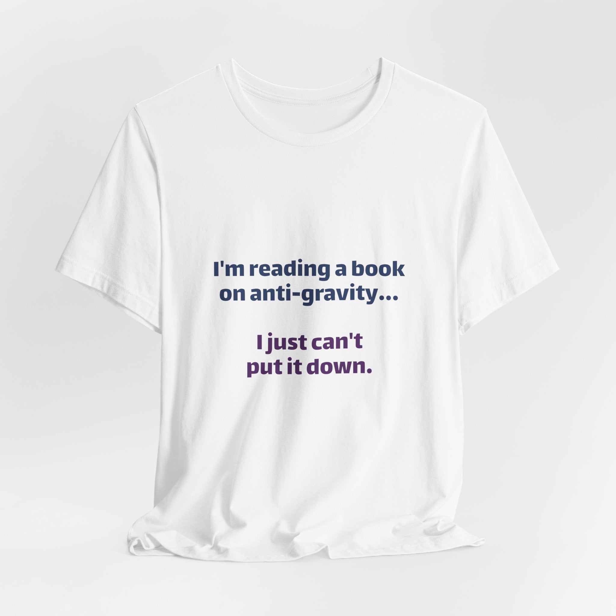 Funny Book Lover T‑Shirt — “I’m reading a book on anti-gravity… I just can’t put it down.”